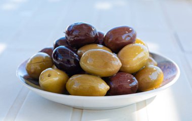 Zeytinyağlı İtalyan yeşil ve siyah zeytinleri beyaz masada servis edilir.