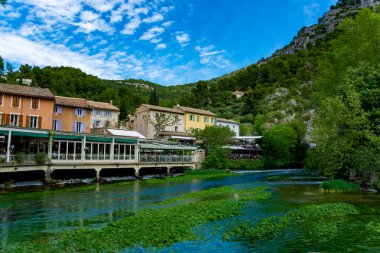 Fransa 'nın güneyinde, Sorgue Nehri' nin zümrüt yeşili sularıyla küçük turistik bir kasaba olan şair Petrarch Fontaine-de-vaucluse görülüyor.