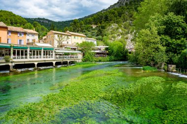 Fransa 'nın güneyinde, Sorgue Nehri' nin zümrüt yeşili sularıyla küçük turistik bir kasaba olan şair Petrarch Fontaine-de-vaucluse görülüyor.