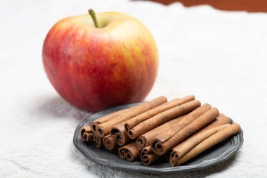 Kış pastası malzemeleri, kurutulmuş aromatik tarçın çubukları ve teneke tabakta elma.
