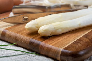 Bir avuç taze pişmemiş kuşkonmaz ve soyma bıçağı, kuşkonmaz soyma, kapama.