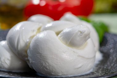 Taze fesleğen ve domatesle servis edilen yumuşak İtalyan mozzarellası şeklinde kıvrılmış.