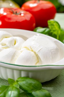 Taze fesleğen ve domatesle servis edilen yumuşak İtalyan mozzarellası şeklinde kıvrılmış.