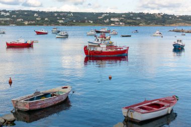 Açık mavi suları ve güneşli bir günde geleneksel renkli Yunan balıkçı tekneleriyle deniz kenarı.
