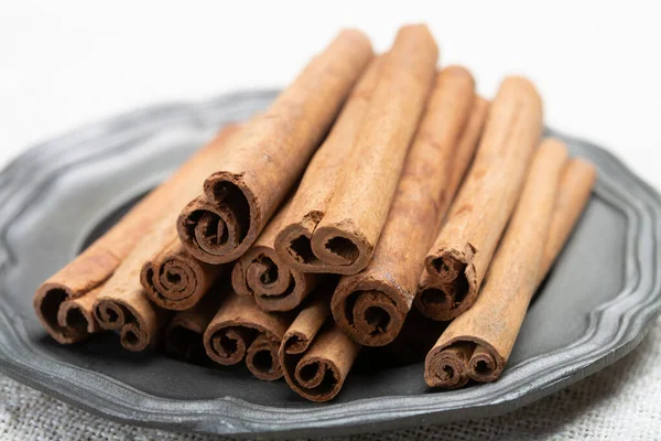 Winter food ingredient, dried aromatic cinnamon sticks on tin plate close up