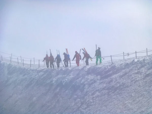 Mountain skiers go together on danger mountain ridge in  snow storm and danger of avalanche, mountain peak Aiguille du Midi in France above ski village Chamonix Mont-Blanc