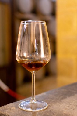 Marsala, Sicilya, İtalya 'da eski meşe fıçılarıyla şarap mahzeninde güçlendirilmiş veya tatlı marsala şarabı tatmak şarap kadehiyle şarap içmek.