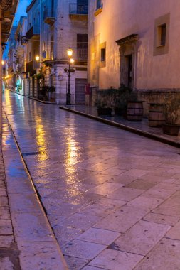 Gece Marsala 'da eski bir cadde yağmur altında sokak lambalarının yansımasıyla, Sicilya, İtalya