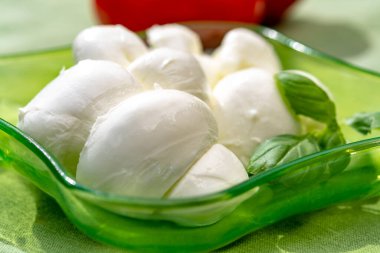 Taze fesleğen ve domatesle servis edilen yumuşak İtalyan mozzarellası şeklinde kıvrılmış.