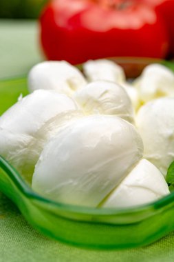 Taze fesleğen ve domatesle servis edilen yumuşak İtalyan mozzarellası şeklinde kıvrılmış.