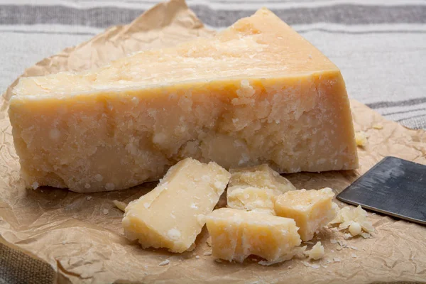 奶酪系列 一块意大利老牌的帕尔梅奶酪和切碎的奶酪刀 — 图库照片