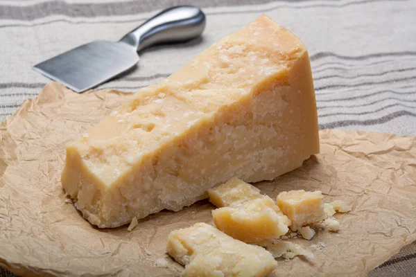 奶酪系列 一块意大利老牌的帕尔梅奶酪和切碎的奶酪刀 — 图库照片