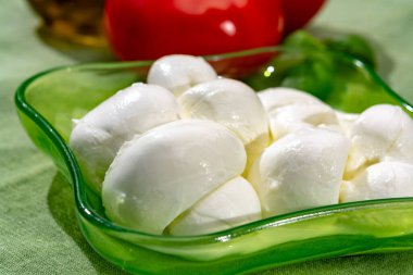 Taze fesleğen ve domatesle servis edilen yumuşak İtalyan mozzarellası şeklinde kıvrılmış.