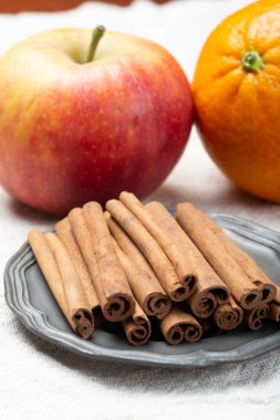 Noel yemeği malzemesi, kurutulmuş aromatik tarçın çubukları teneke tabakta, elma ve portakal meyveleri kapanıyor.