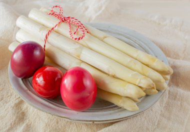 Beyaz kuşkonmaz hasadı ve renkli Paskalya yumurtaları, bahar mevsiminde yüksek kaliteli çiğ kuşkonmaz, Paskalya yemeği için malzemeler.
