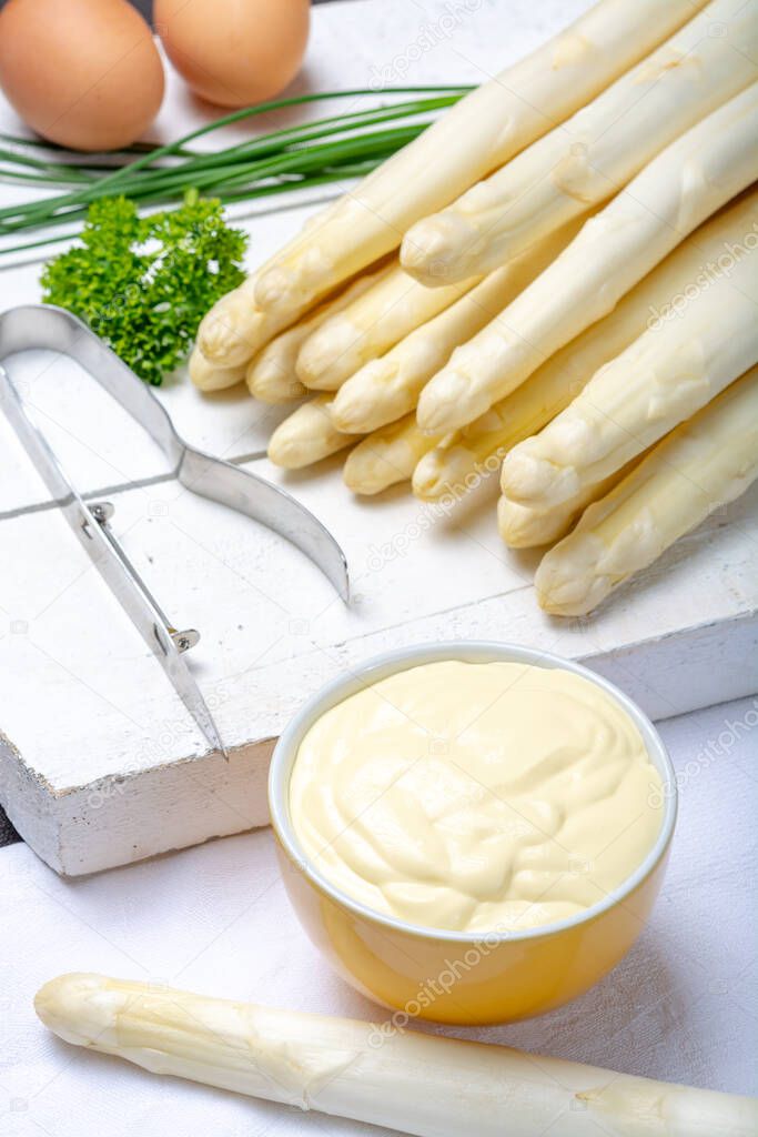 White hollandaise sauce in bowl, traditional sauce for dishes with cooked white asparagus close up