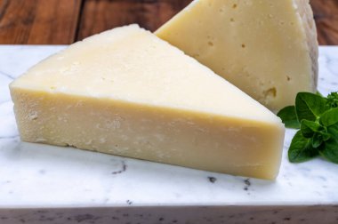 Pieces of matured pecorino romano italian cheese made from sheep milk in Lazio, Sardinia or Tuscany close up clipart