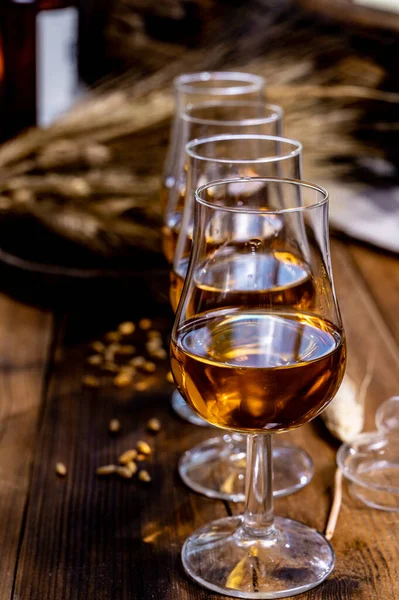 古い暗い木製のヴィンテージテーブルの上に古いスコッチウイスキーやアメリカのバーボンとグラスを試飲大麦粒 — ストック写真
