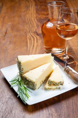 İspanyol peyniri koleksiyonu, aromatik kurutulmuş biberiye ve cam içinde soğuk gül şarabından yapılmış koyun sert peyniri parçaları.