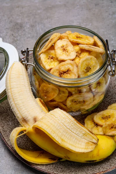 Sağlıklı tatlı atıştırmalık, gevrek, susuz, şekersiz, cam kavanozda muz cipsi.
