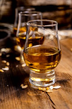 Arpa tanecikli, eski, siyah ahşap masadaki, yıllanmış viski ile küçük bardakları tadıyorum.