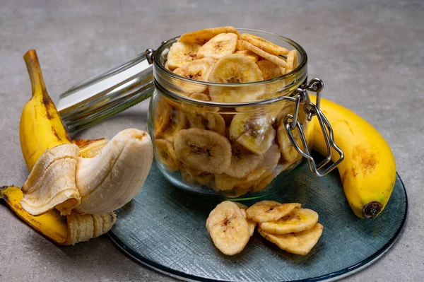 Healthy sweet snack, crispy dehydrated unsugared banana chips in glass jar