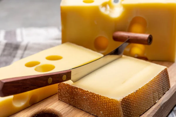 Swiss cheeses, block of medium-hard yellow cheese emmental or emmentaler with round holes and matured gruyere close up