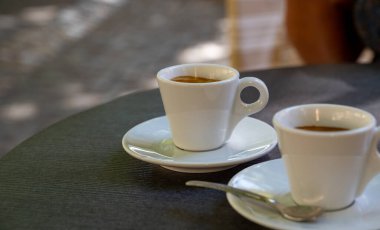 Kapalı kafedeki terasta koyu siyah espresso içiyorum.
