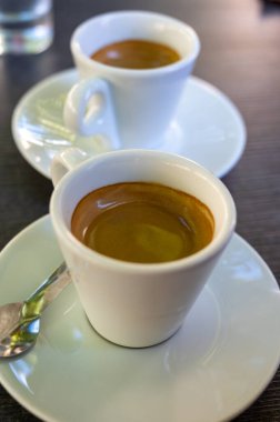 Kapalı kafedeki terasta koyu siyah espresso içiyorum.