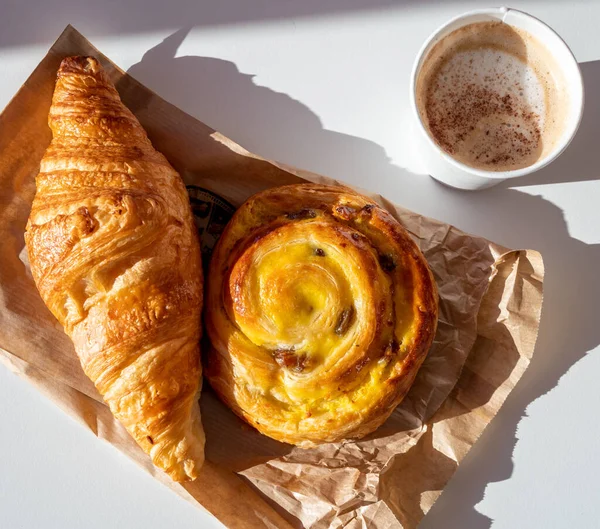 French breakfast in bakery served outdoor, cups of coffee and fresh baked croissants and pastry, morning food close up