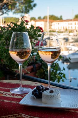 Yaz aylarında yerel gül şarabı ve yumuşak Fransız keçi peyniri tatmak ve arka planda Port Grimaud limanı, Provence, Var, Fransa