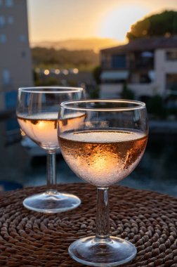 Drinking of local cold rose wine at sunset in summer with sail boats haven of Port grimaud on background, Provence, Var, France clipart