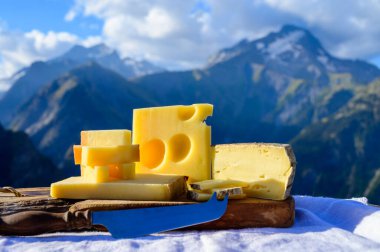 Peynir koleksiyonu, Fransız beaufort, abondance, emmental, tomme de savoie cheeses Savoy bölgesinde açık havada servis edilir, yaz aylarında Alp dağlarının zirveleri arka plandadır.