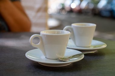 Kapalı kafedeki terasta koyu siyah espresso içiyorum.