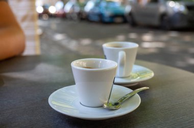 Kapalı kafedeki terasta koyu siyah espresso içiyorum.