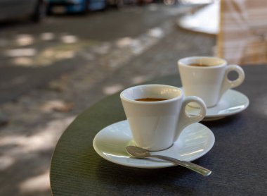 Kapalı kafedeki terasta koyu siyah espresso içiyorum.