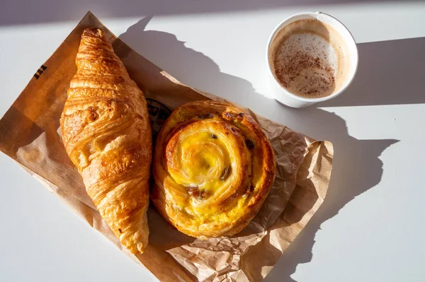 French breakfast in bakery served outdoor, cups of coffee and fresh baked croissants and pastry, morning food close up