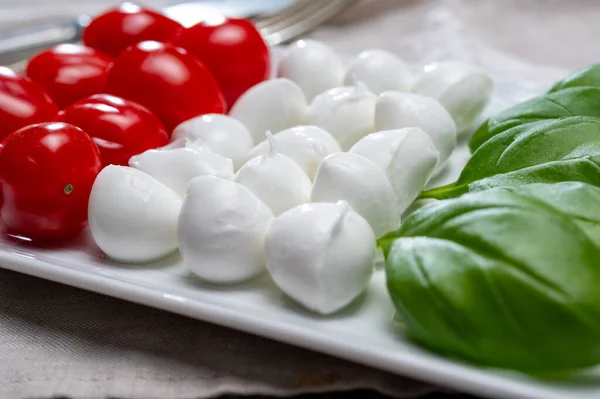 Italian food served as flag of Italy Tricolore with fresh fresh green basil, white mini mozzarella cheese and red cherry tomatoes close up