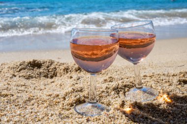Beyaz kumlu sahilde iki bardak yerel gül şarabı ve arka planda mavi Akdeniz, Le Lavandou, Var, Provence, Fransa yakınlarında