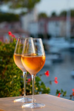 Yaz günbatımında yerel soğuk gül şarabının tadına bakmak arka planda liman, Provence, Var, Fransa