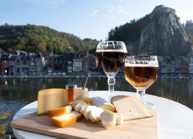 Bir bardak Belçika manastırı birası ve trapist birayla yapılan peynirleri tatmak ve Belçika, Dinant 'taki Maas nehri manzaralı güzel otlar.