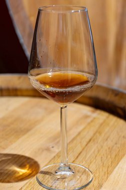 Eski büyük meşe fıçılarıyla şarap mahzenini ziyaret etmek, Marsala, Sicilya, İtalya ve şarap endüstrisindeki varillerden alınmış bir bardak güçlendirilmiş veya lezzetli marsala şarabı.