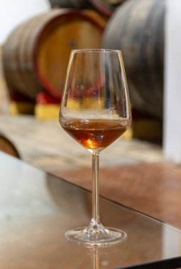 Eski büyük meşe fıçılarıyla şarap mahzenini ziyaret etmek, Marsala, Sicilya, İtalya ve şarap endüstrisindeki varillerden alınmış bir bardak güçlendirilmiş veya lezzetli marsala şarabı.