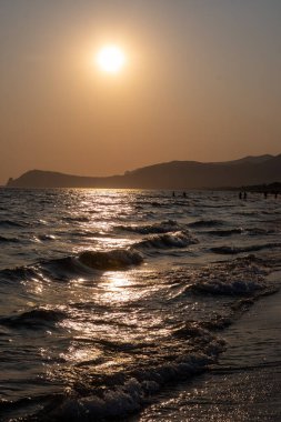 Güneş ışığında gün batımında yüzen insanların siluetleri, Sperlonga yakınlarındaki kumlu plajlar, Lazio, İtalya, yaz tatili