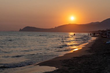 Güneş ışığında gün batımında yüzen insanların siluetleri, Sperlonga yakınlarındaki kumlu plajlar, Lazio, İtalya, yaz tatili