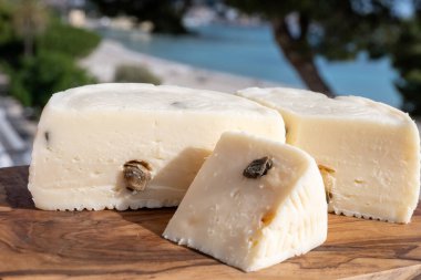 Primo İndirimli Sert Peynir. Karışık sütten yapılmış. Sicilya sepetinin ince kabuğu ve deseni turşulu kapari ve Sicilya, Mondello sahilinde deniz manzaralı.