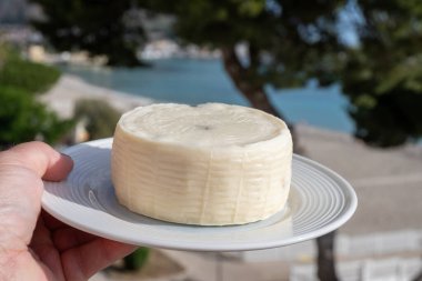 Primo İndirimli Sert Peynir. Karışık sütten yapılmış. Sicilya sepetinin ince kabuğu ve deseni turşulu kapari ve Sicilya, Mondello sahilinde deniz manzaralı.