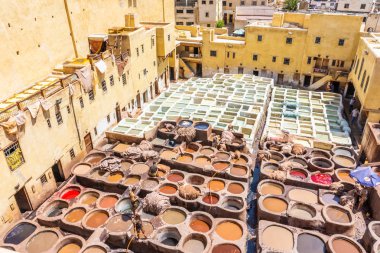 Workers tanning and dyeing in red hides in the vats of Fez tanneries, Morocco  clipart