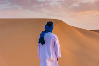 Şafak vakti Sahra Çölü 'nde geleneksel Tuareg giysileri giyen Berber adam, Merzouga, Fas