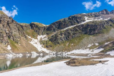 Gran Paradiso Ulusal Parkı 'ndaki karlı arazide güzel zümrüt Alp Gölü
